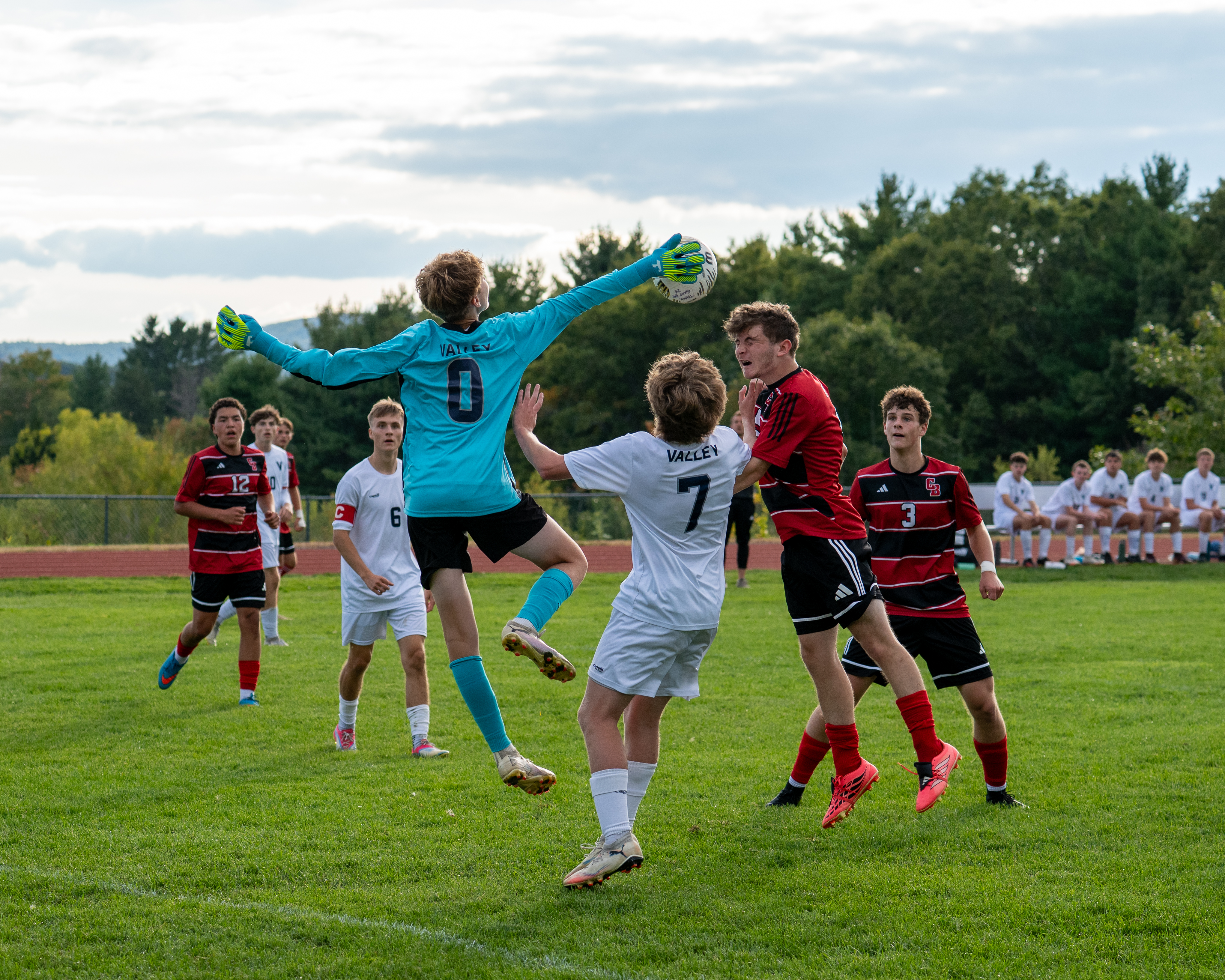 Soccer goalkeeper leaping to make a save during a high school game