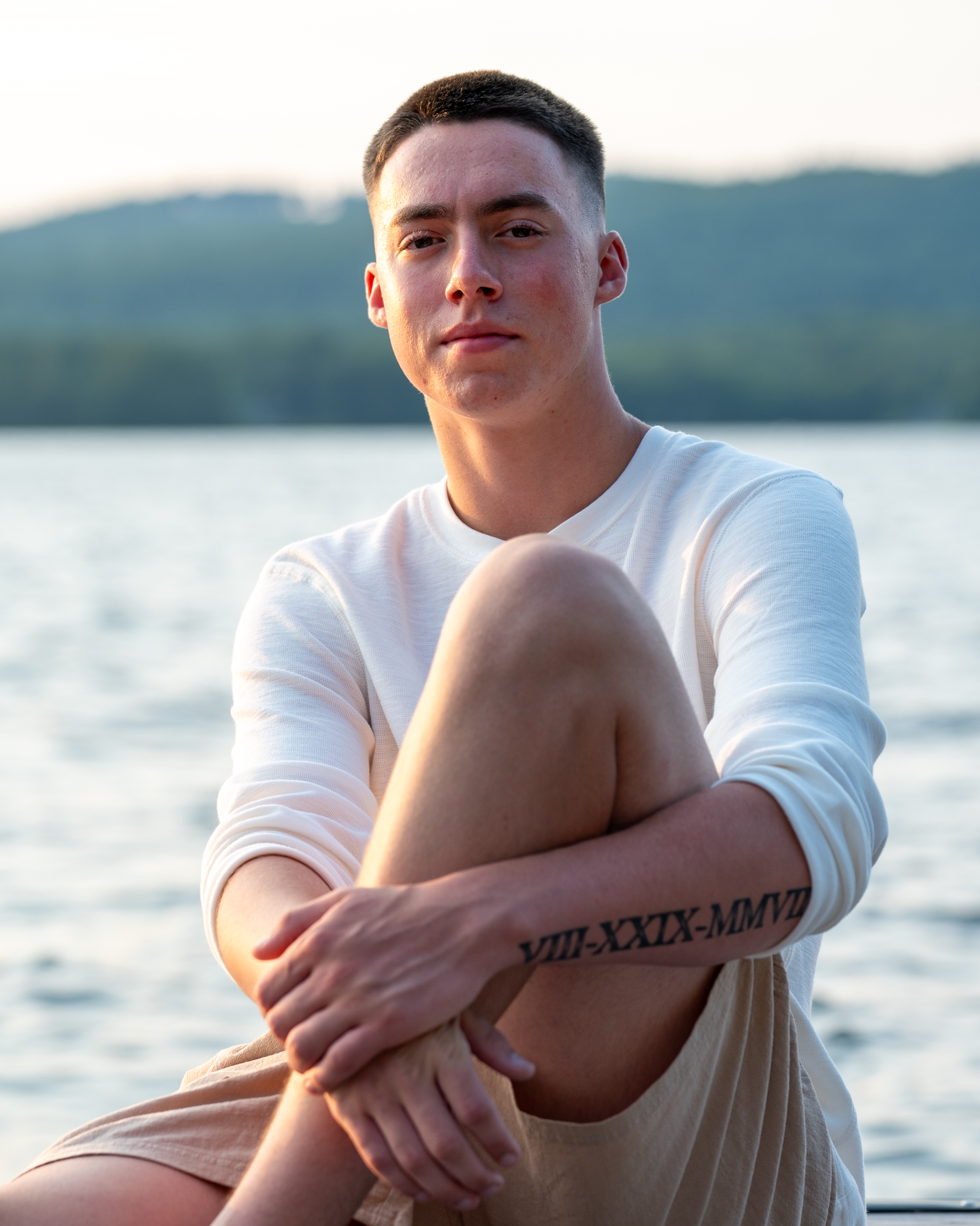 High school senior sitting by a New Hampshire lake at sunset
