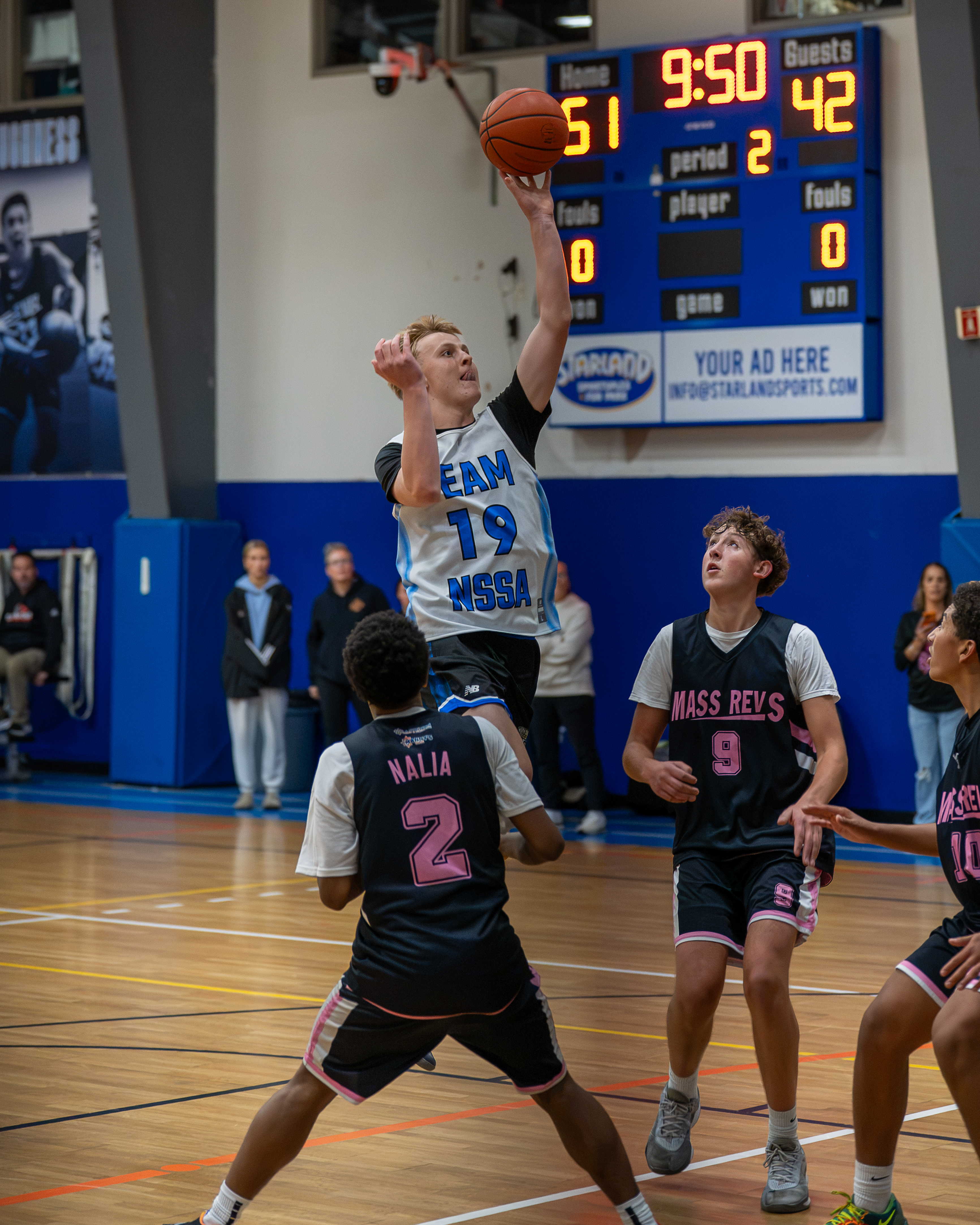 NSSA player rising for a jump shot with the scoreboard reading 51-42 against Mass Revs