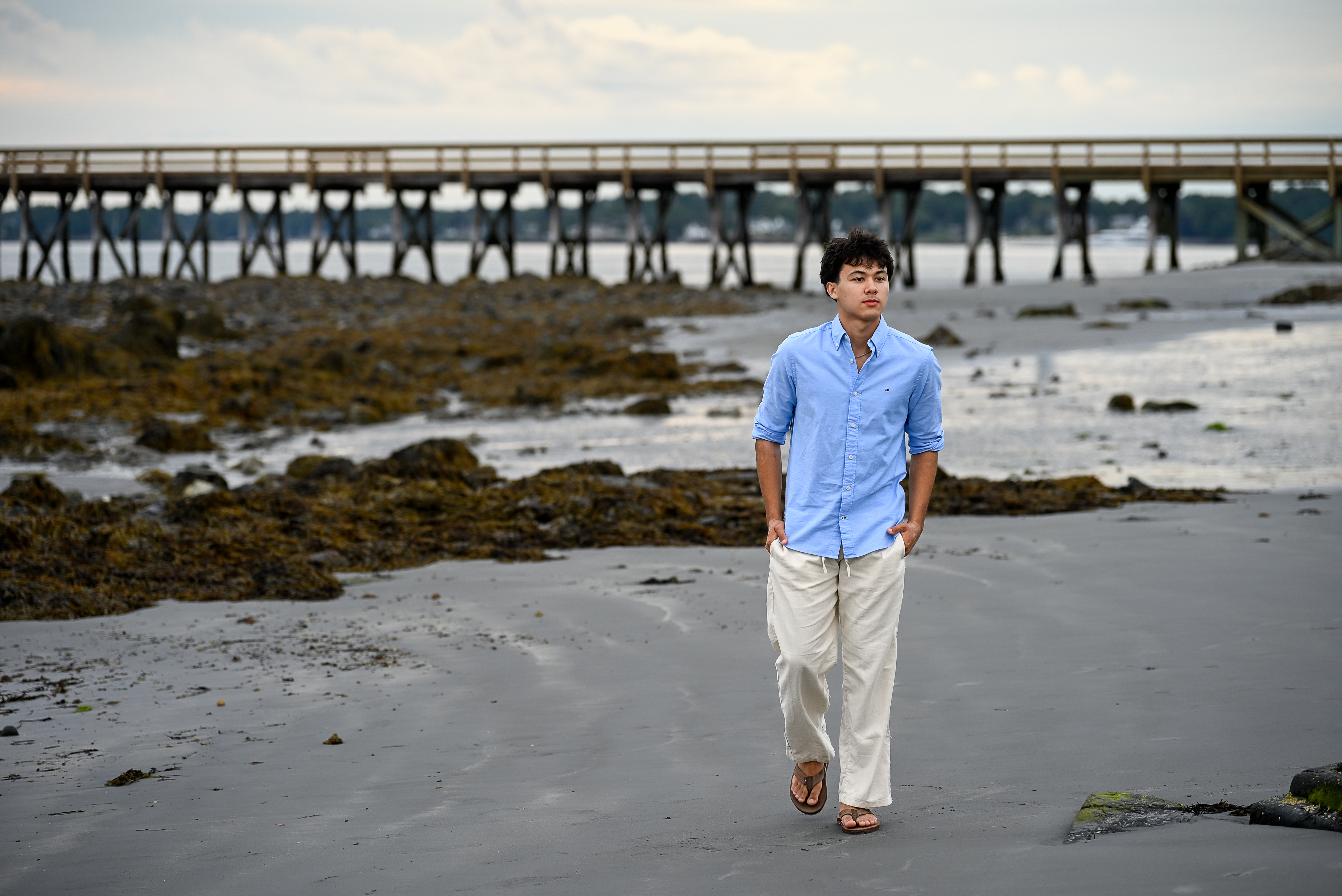 Senior portrait walking along the beach at Fort Foster with the pier in the background